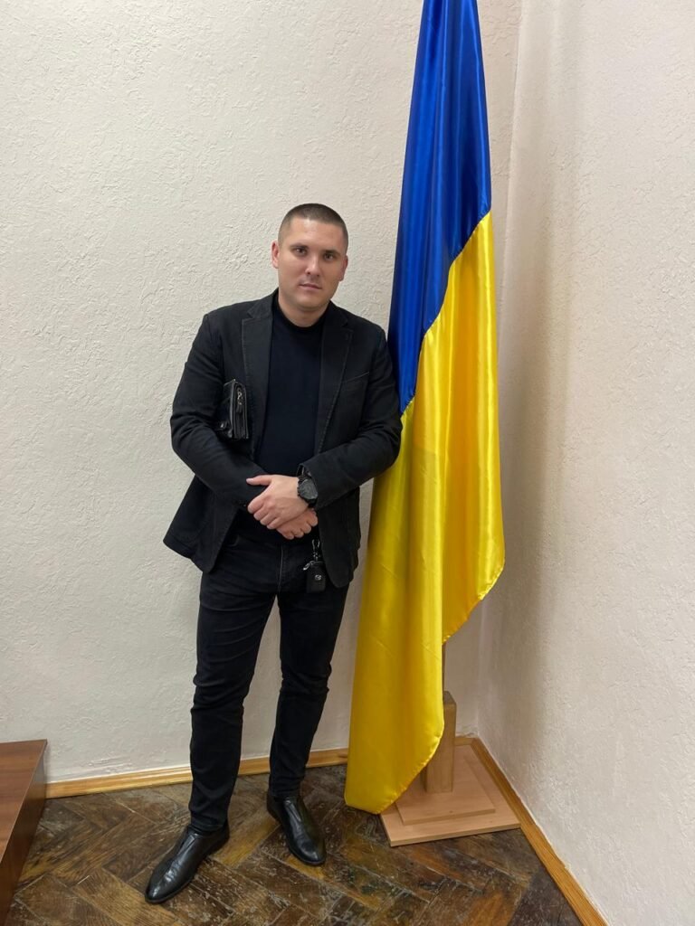 Гур Юрій Ігорович — психолог, кризовий консультант, офіційне фото біля прапора України