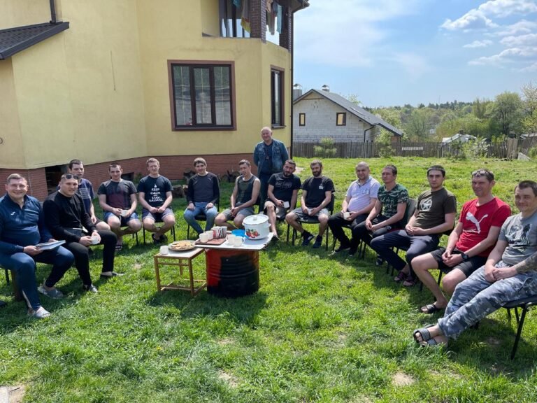 Юрій Гур проводить групову зустріч з учасниками програми реабілітації на подвір'ї центру